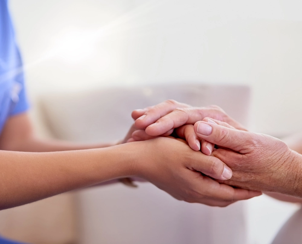 Schmerzen Demenz Eine Betreuerin hält die Hände einer Seniorin