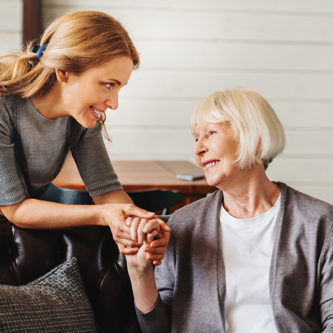 Pflegekraft unterstützt lächelnde Seniorin im Rollstuhl in heller, freundlicher Umgebung